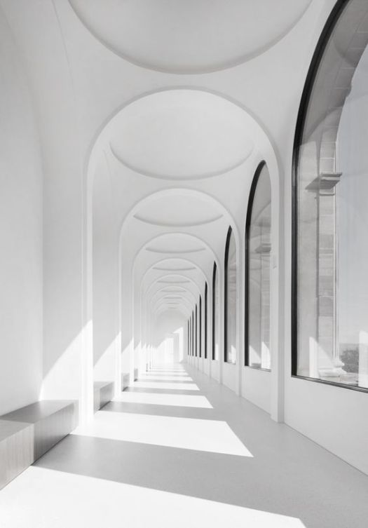 Black rimmed arch windows and white arches down a long corridor