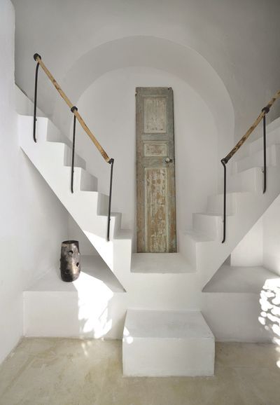 Distressed door in a white room with two staircases and an arched recess